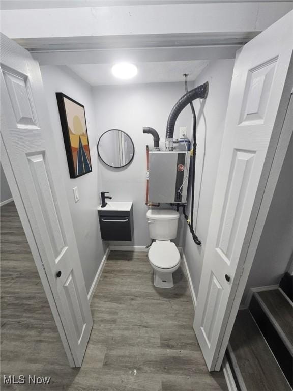 half bath with vanity, wood finished floors, toilet, and baseboards