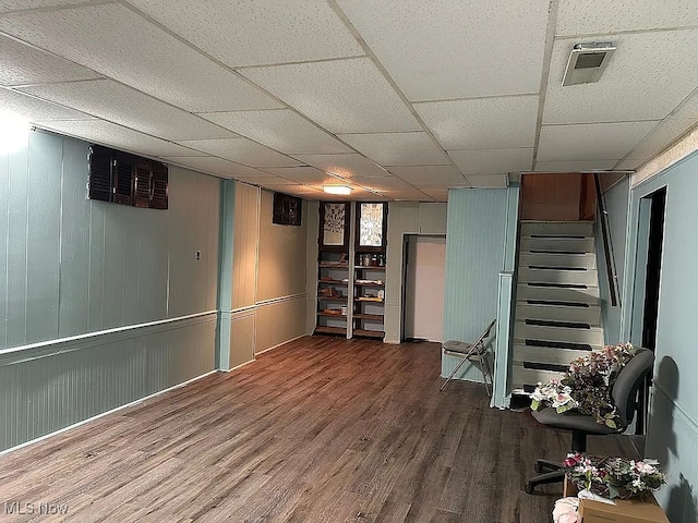 finished basement featuring stairs, a paneled ceiling, wood finished floors, and visible vents