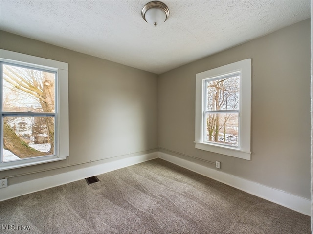 unfurnished room featuring carpet, visible vents, a textured ceiling, and baseboards