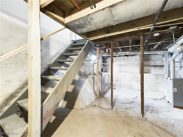 unfinished below grade area featuring stairway and heating unit