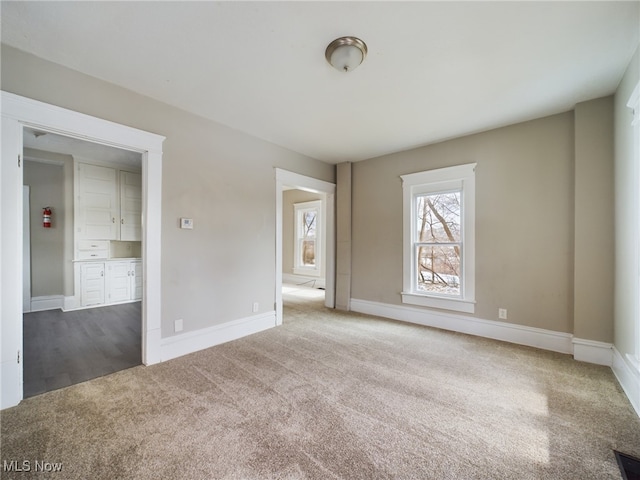 carpeted spare room featuring baseboards