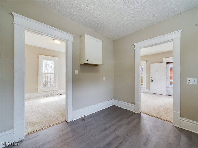 spare room featuring dark wood-type flooring, dark colored carpet, and baseboards