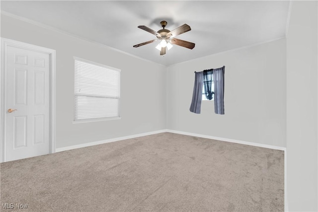 carpeted spare room featuring crown molding, baseboards, and a ceiling fan