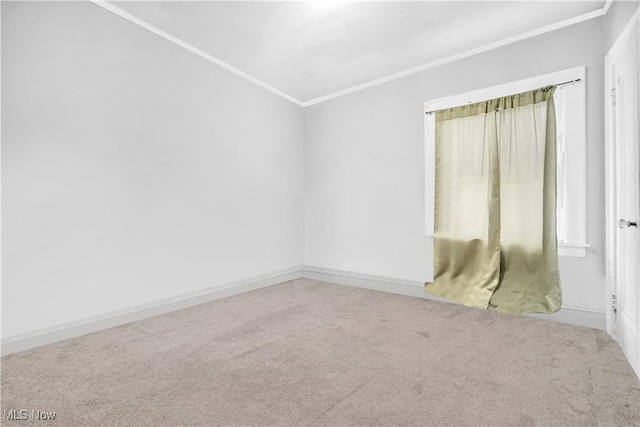 carpeted spare room featuring baseboards and ornamental molding