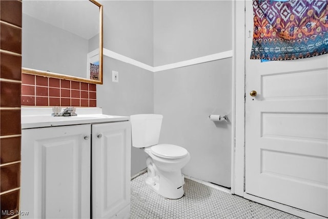 bathroom featuring tile patterned floors, backsplash, toilet, and vanity