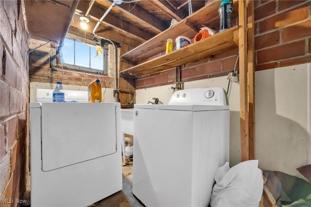 washroom with washer and dryer, laundry area, and brick wall