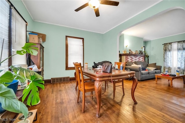 dining space featuring arched walkways, ornamental molding, hardwood / wood-style flooring, and visible vents