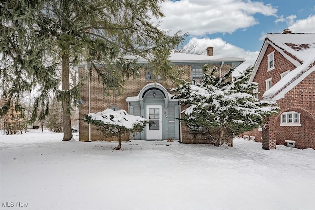 view of front facade with a chimney and brick siding