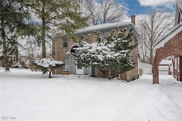 view of snowy exterior featuring a garage and brick siding