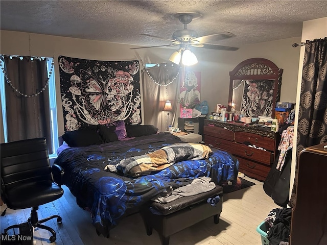 bedroom with a textured ceiling, hardwood / wood-style flooring, and a ceiling fan