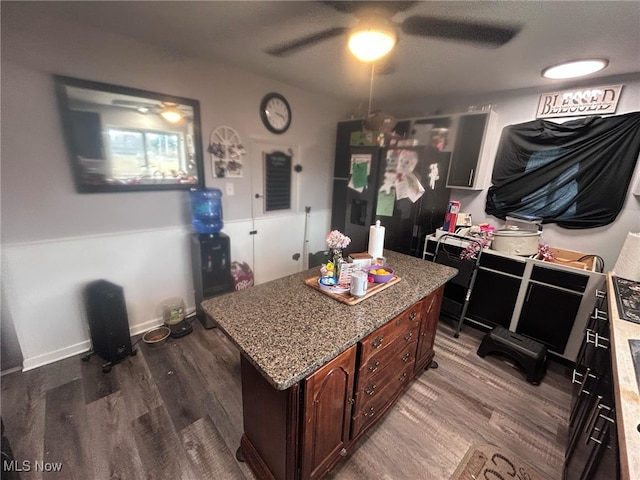 kitchen featuring a ceiling fan, a center island, baseboards, and wood finished floors