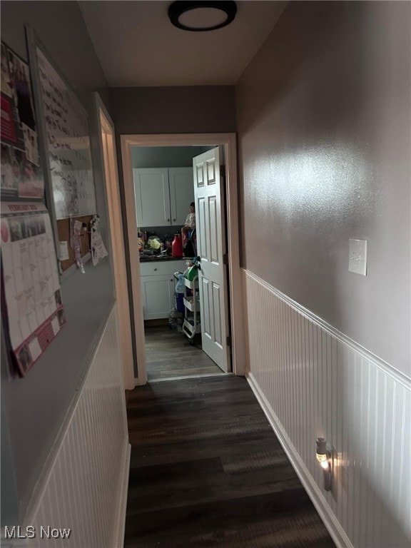 corridor with dark wood finished floors and wainscoting