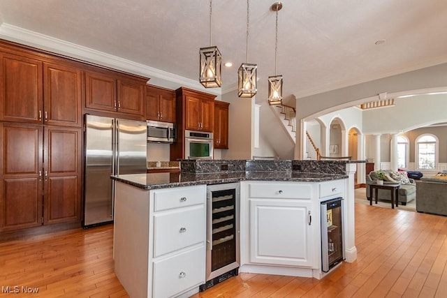 kitchen featuring light wood-style flooring, beverage cooler, stainless steel appliances, and open floor plan