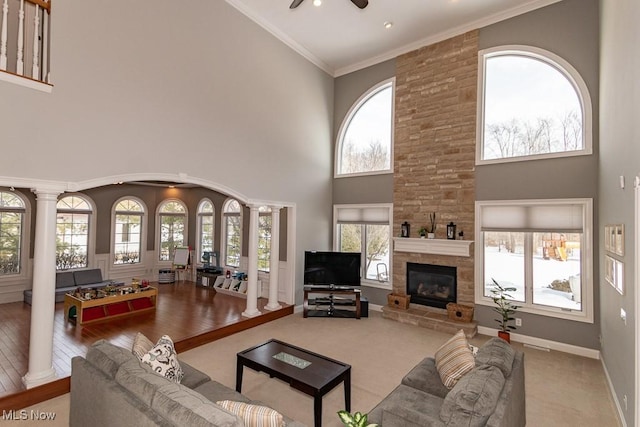 living area with crown molding, a wealth of natural light, and decorative columns