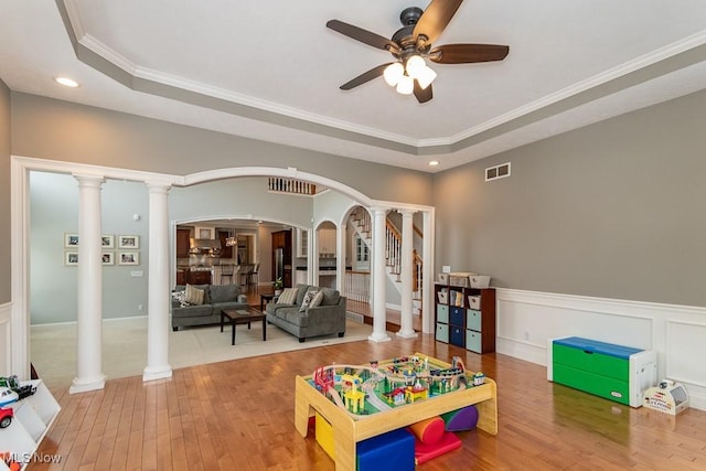 recreation room featuring arched walkways, decorative columns, visible vents, wainscoting, and hardwood / wood-style floors