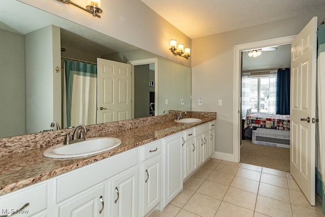 ensuite bathroom featuring baseboards, double vanity, a sink, and tile patterned floors