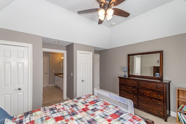 bedroom featuring a ceiling fan, lofted ceiling, baseboards, and two closets