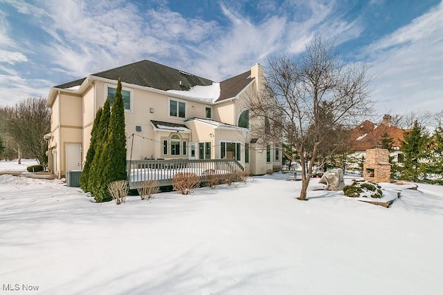 snow covered property with cooling unit and a wooden deck