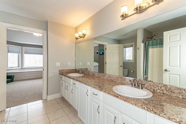 bathroom with double vanity, tile patterned flooring, a sink, and toilet