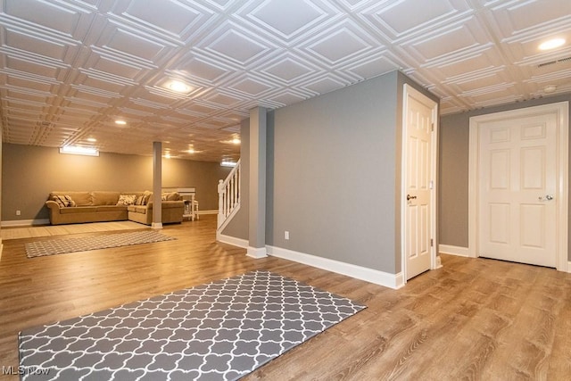 finished basement featuring stairs, wood finished floors, an ornate ceiling, and baseboards