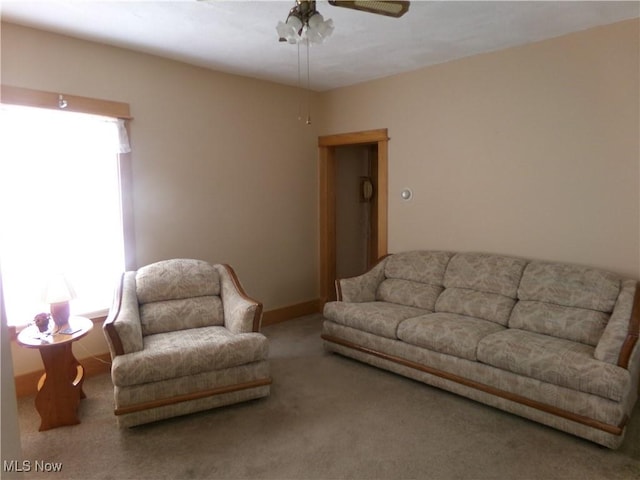 carpeted living room with a ceiling fan and baseboards