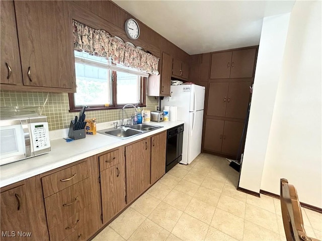 kitchen featuring white appliances, baseboards, a sink, light countertops, and backsplash