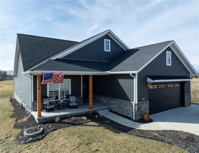 view of front of home with a garage, stone siding, driveway, and roof with shingles