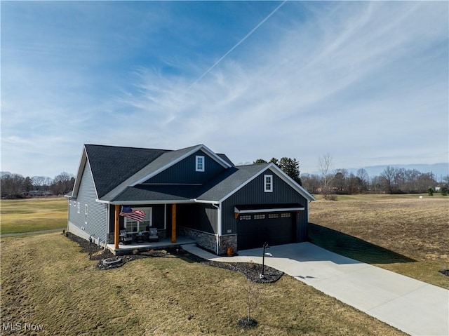 view of front of property featuring driveway, stone siding, a porch, and a front yard