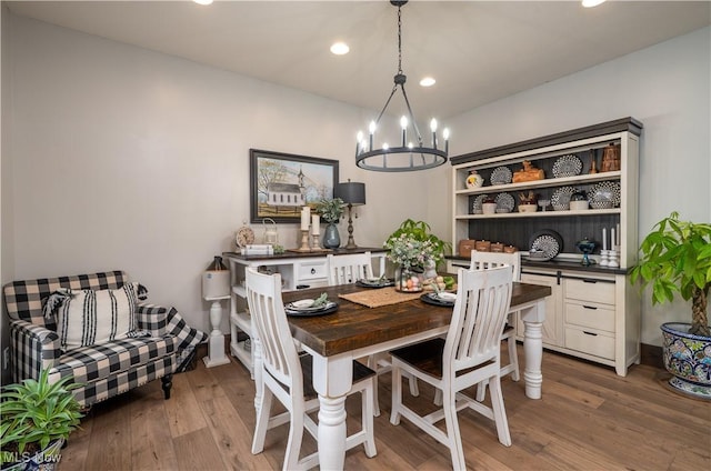 dining space with recessed lighting, a notable chandelier, and wood finished floors