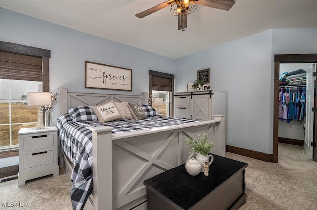 bedroom with light carpet, a ceiling fan, baseboards, a spacious closet, and a closet