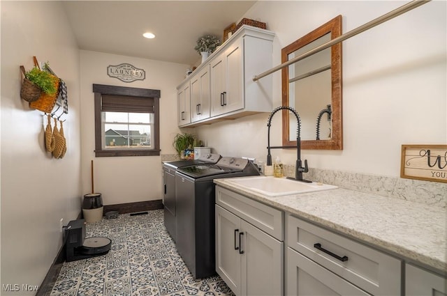 laundry area featuring tile patterned flooring, separate washer and dryer, a sink, baseboards, and cabinet space