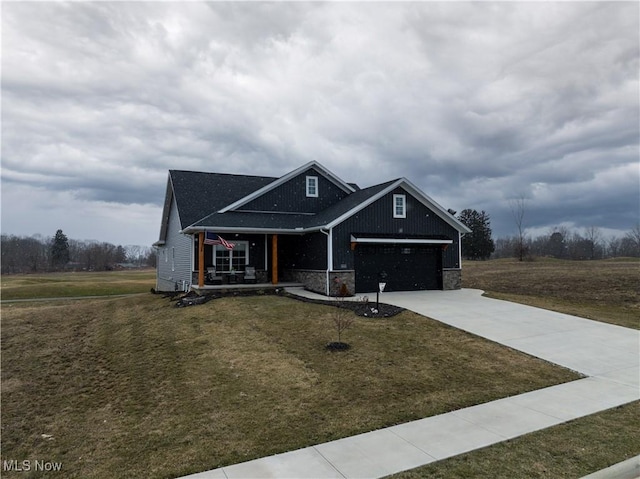 view of front facade featuring a porch, a garage, driveway, stone siding, and a front lawn