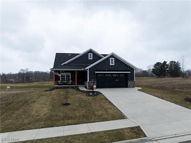 view of front facade with a garage, a front yard, concrete driveway, and stone siding