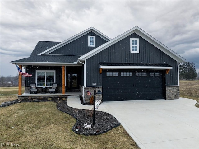 view of front of property featuring metal roof, an attached garage, a shingled roof, stone siding, and driveway