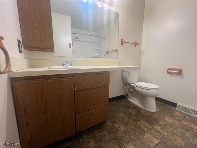 bathroom with toilet, vanity, visible vents, baseboards, and a shower