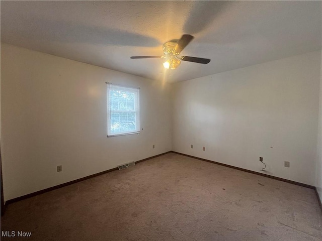 empty room with light colored carpet, ceiling fan, visible vents, and baseboards