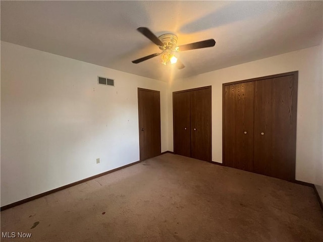 unfurnished bedroom with a ceiling fan, visible vents, baseboards, carpet, and two closets