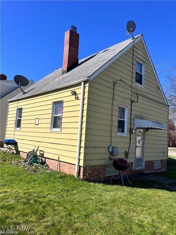 rear view of house with crawl space, a yard, and a chimney