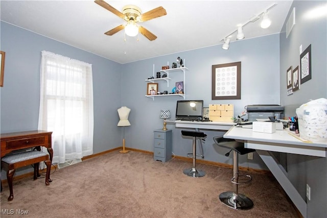 office space featuring carpet floors, rail lighting, ceiling fan, and baseboards