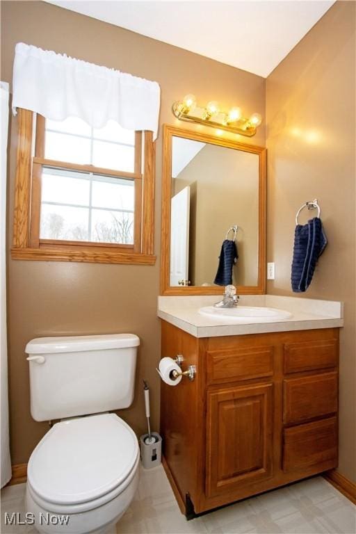 bathroom with baseboards, vanity, and toilet