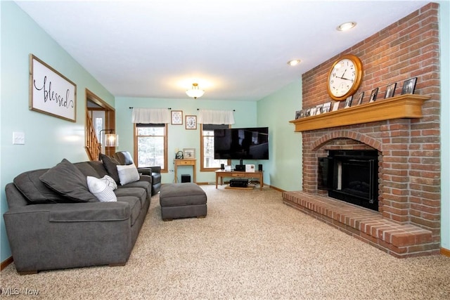 carpeted living room with a brick fireplace, stairway, and baseboards