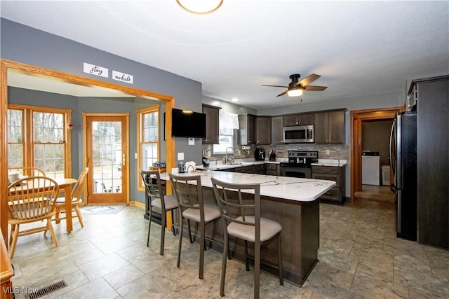 kitchen featuring visible vents, appliances with stainless steel finishes, a peninsula, a kitchen bar, and a sink