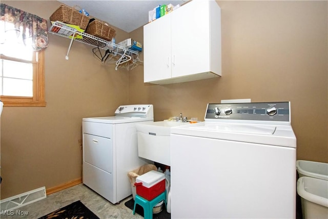 laundry room with washing machine and clothes dryer, cabinet space, visible vents, a sink, and baseboards