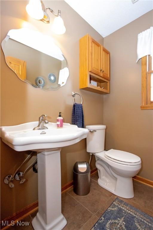 bathroom with tile patterned flooring, baseboards, and toilet