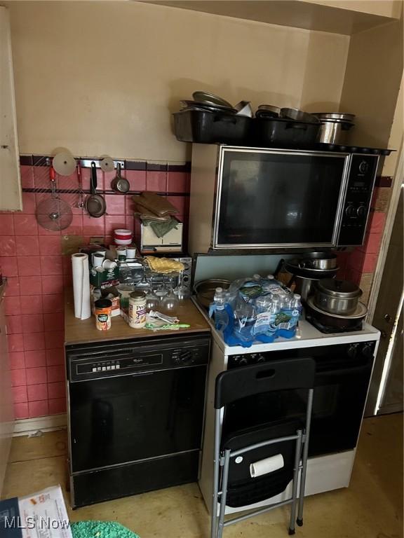 kitchen featuring wainscoting, dishwasher, tile walls, and stove