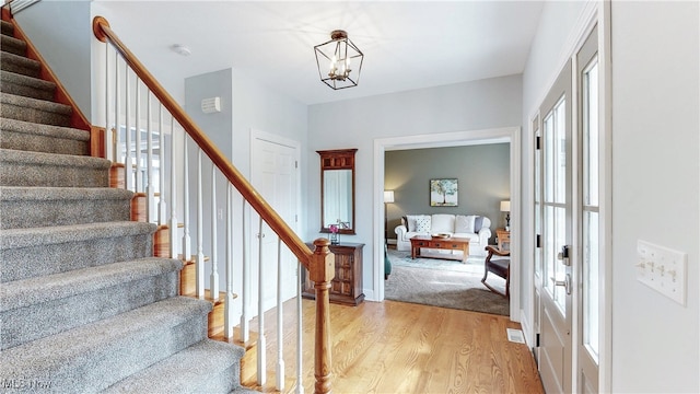 entryway featuring stairs, baseboards, light wood-style flooring, and a notable chandelier