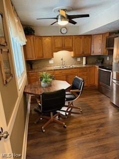 kitchen with brown cabinets, stove, freestanding refrigerator, a sink, and wood finished floors