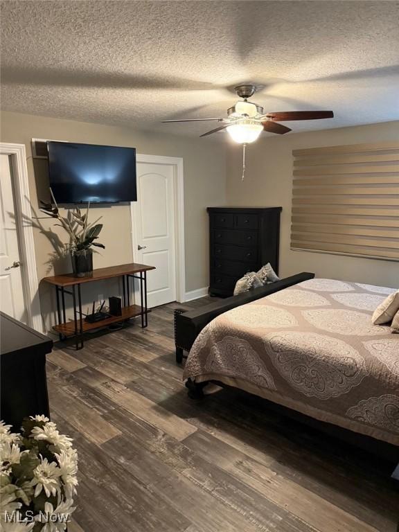 bedroom with a ceiling fan, a textured ceiling, baseboards, and wood finished floors