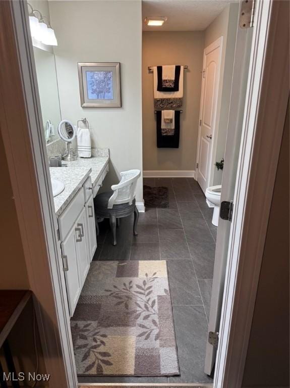 bathroom featuring toilet, tile patterned flooring, baseboards, and vanity