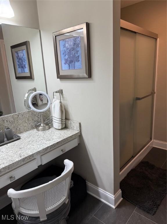 bathroom with a stall shower, vanity, baseboards, and tile patterned floors